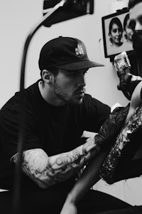 a black and white photo of a man getting tattooed